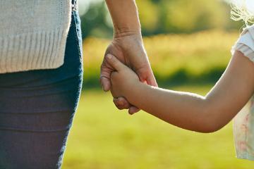 An adult holding a child's hand